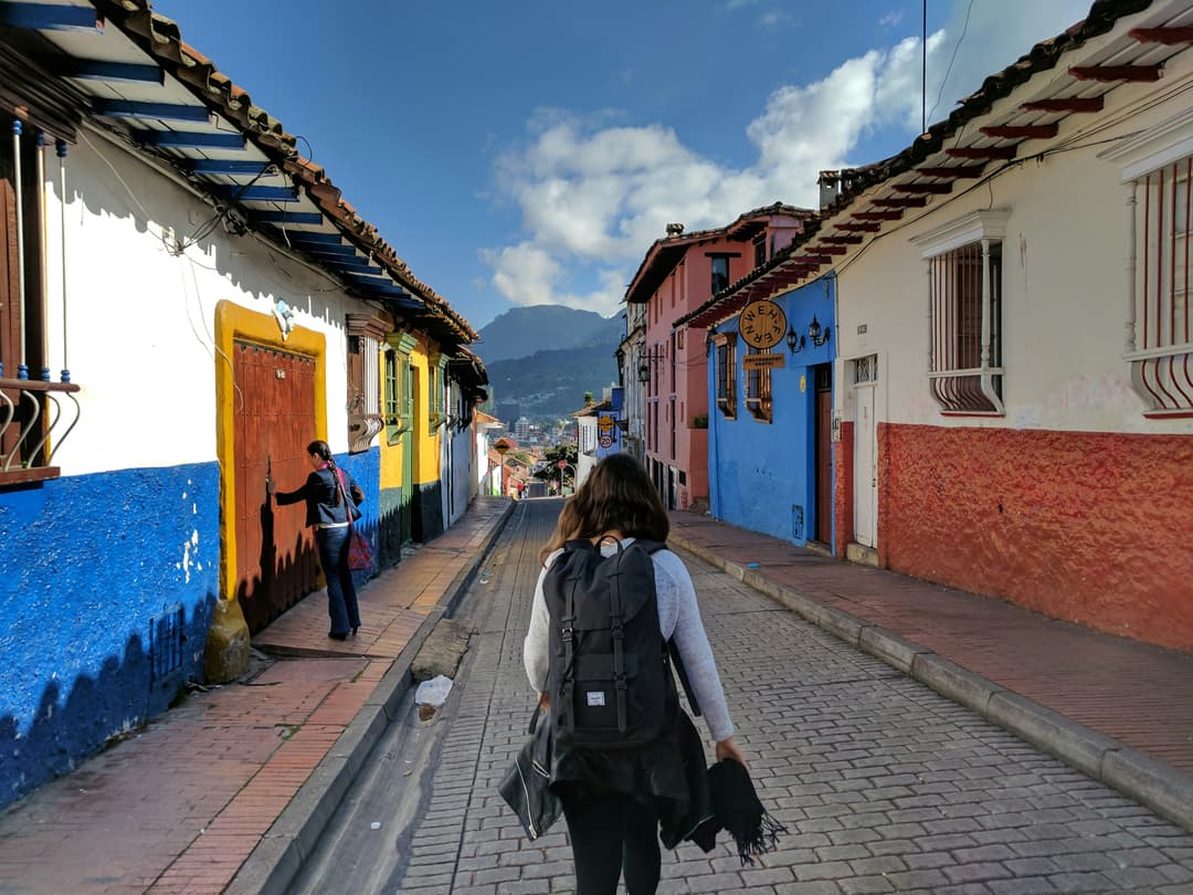 Young backpacker walking through a vibrant, colourful street in a foreign country, symbolizing long-term travel and expat adventures