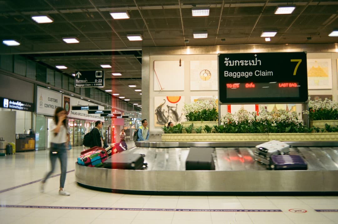 Suitcases rotating on an airport baggage claim carousel, representing lost or delayed baggage coverage in travel insurance packages.