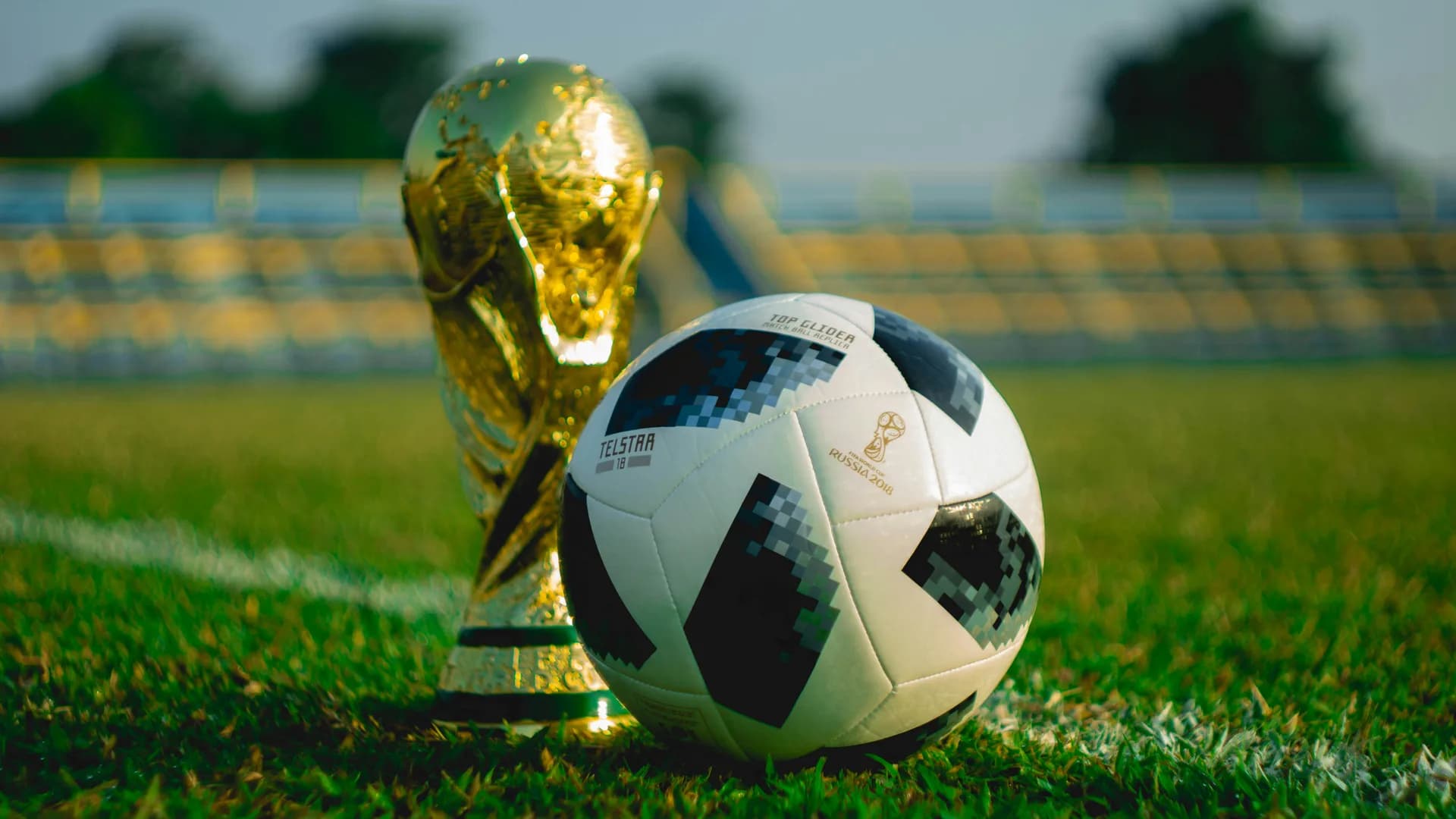 World Cup trophy and official match ball resting on a soccer pitch